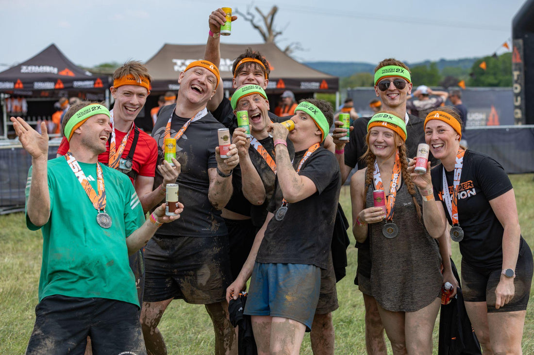 Tough Mudder finishers in headbands and medals raising Hard Rock Cocktails cans